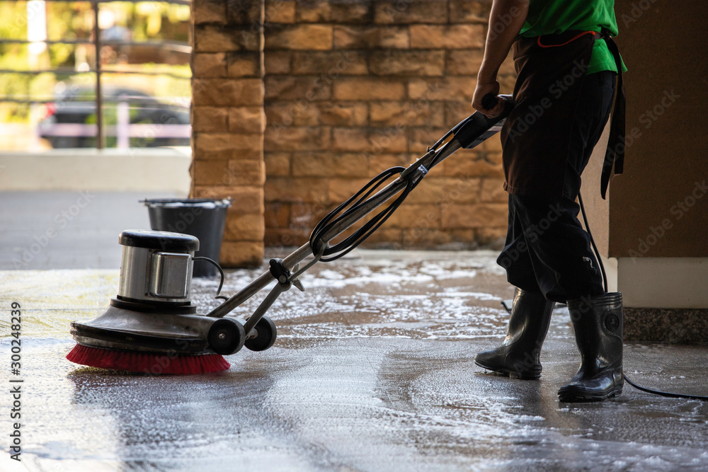 A man worker cleaning the floor with polishing machine