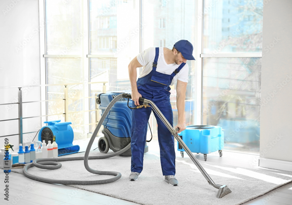 Dry cleaner's employee removing dirt from carpet in flat