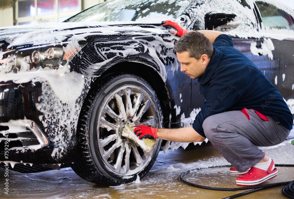 Man worker washing car's alloy wheels on a car wash