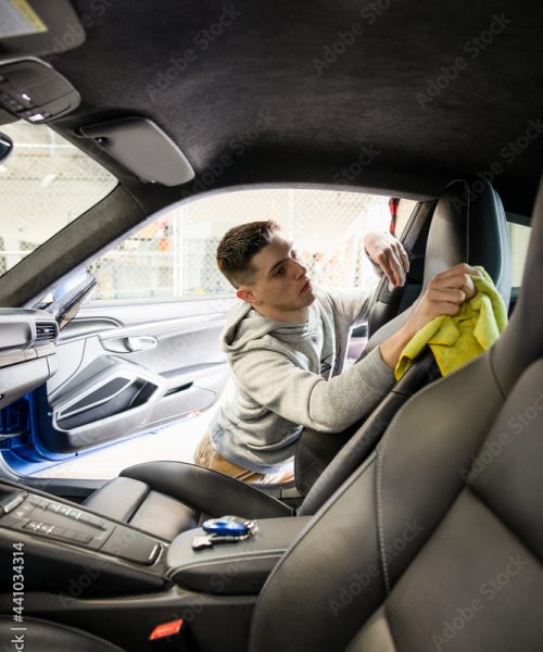 Male worker detailing inside of sports car