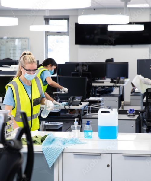 Team wearing hi vis vest and face mask cleaning the office using disinfectant