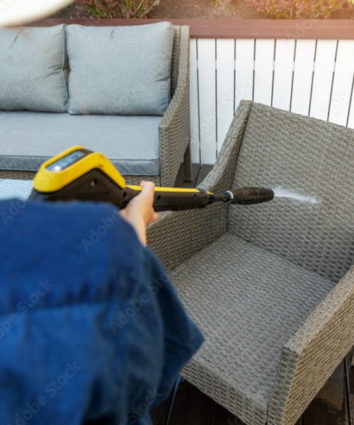 woman doing garden terrace furniture cleaning with high pressure washer